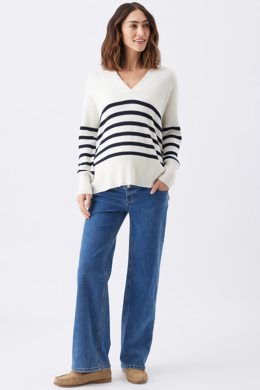 Woman wearing a striped sweater and blue jeans on a white background
